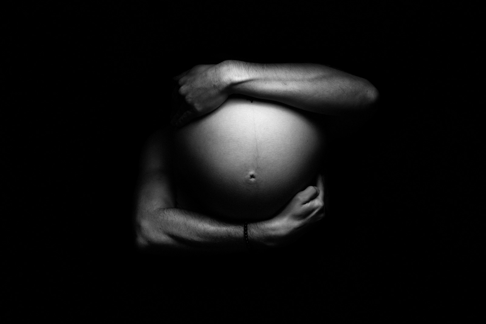 Femme enceinte et papa tenant tendrement son ventre, illustrant l'importance de créer un lien fort avec son bébé dès la grossesse. Le contact physique, la communication et les moments de connexion renforcent l'attachement prénatal et favorisent le bien-être de la mère et du bébé